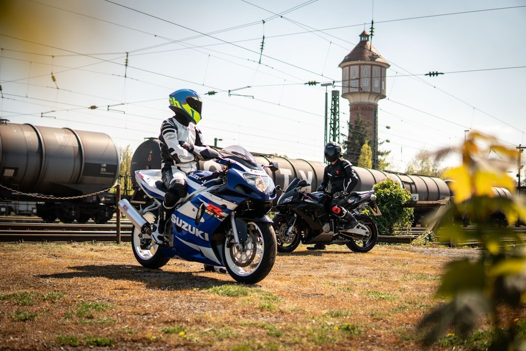 Two bikers are posing near train tracks.