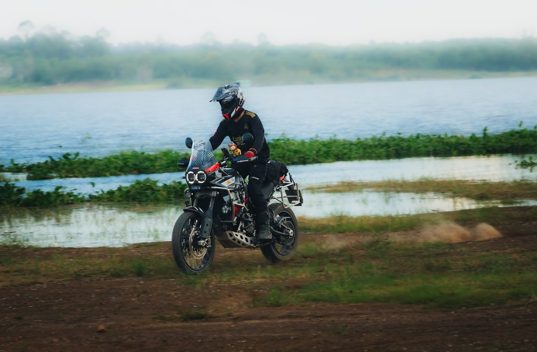 Motorcyclist riding on dirt near a body of water