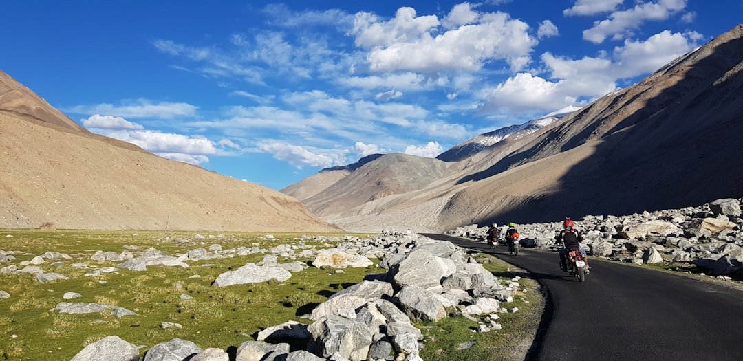 people sitting on rock near brown mountain under blue sky during daytime