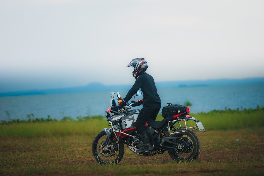 Rider on adventure motorcycle near a large body of water.