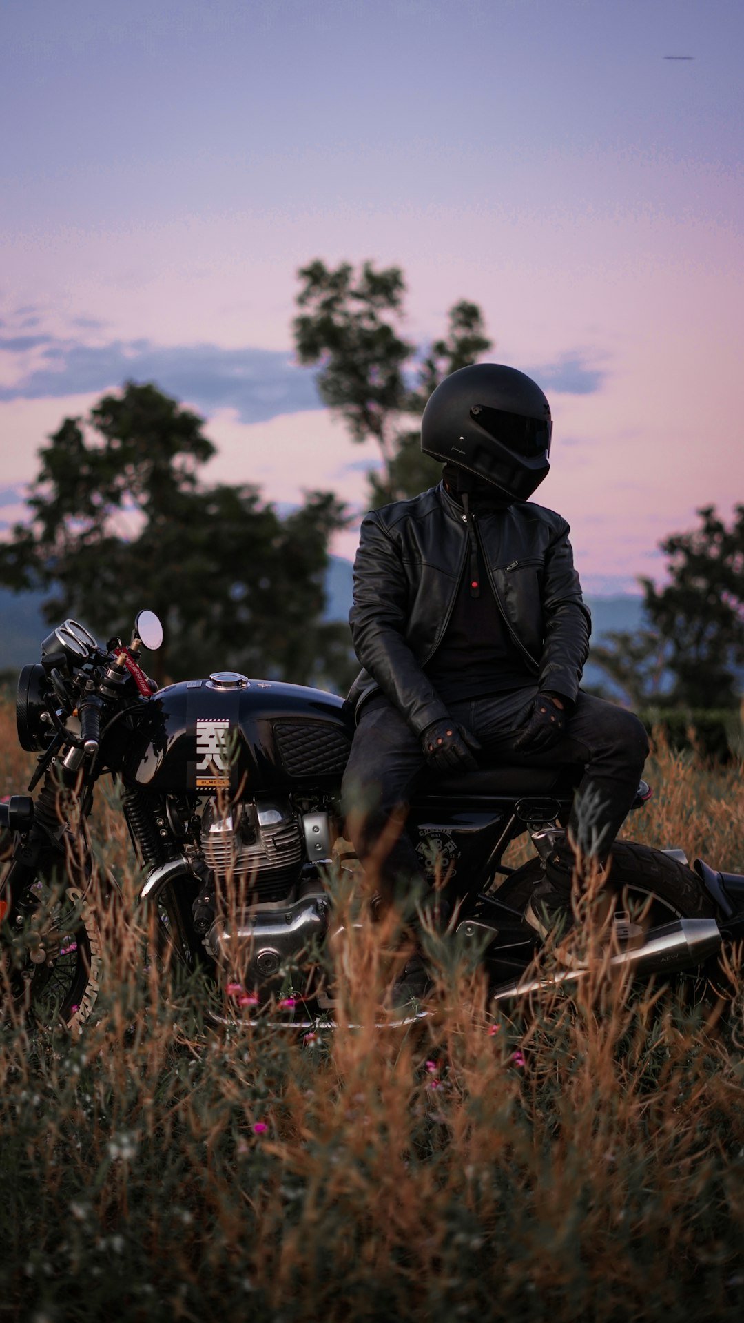a man sitting on a motorcycle in a field