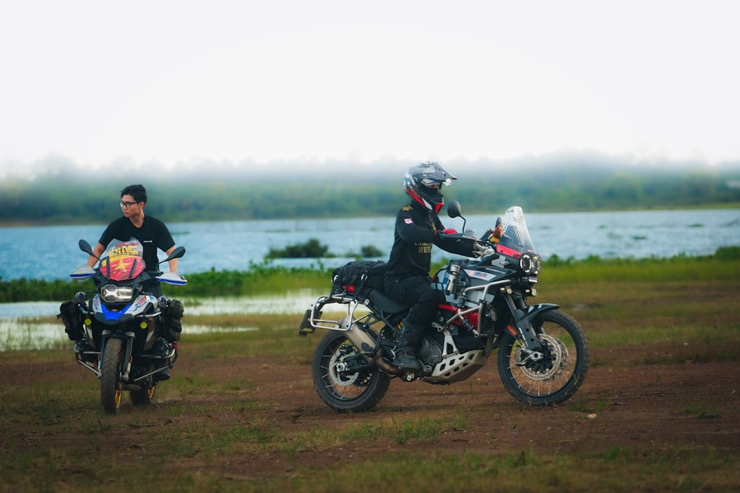 Two motorcyclists with adventure bikes by a lake