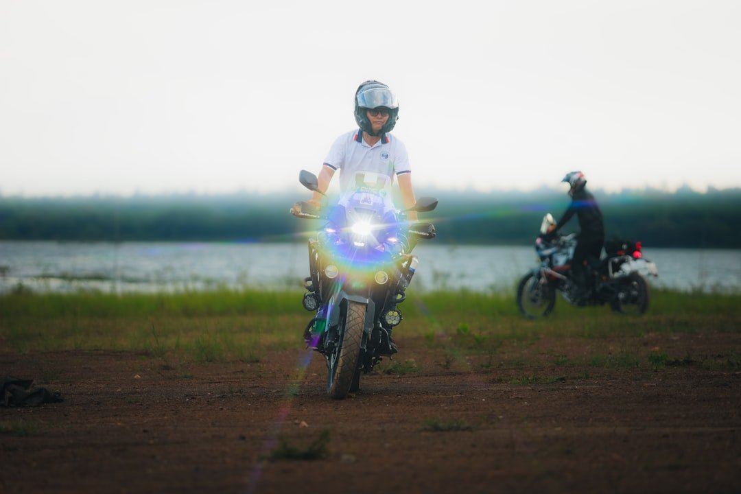 Two people on motorcycles near a lake
