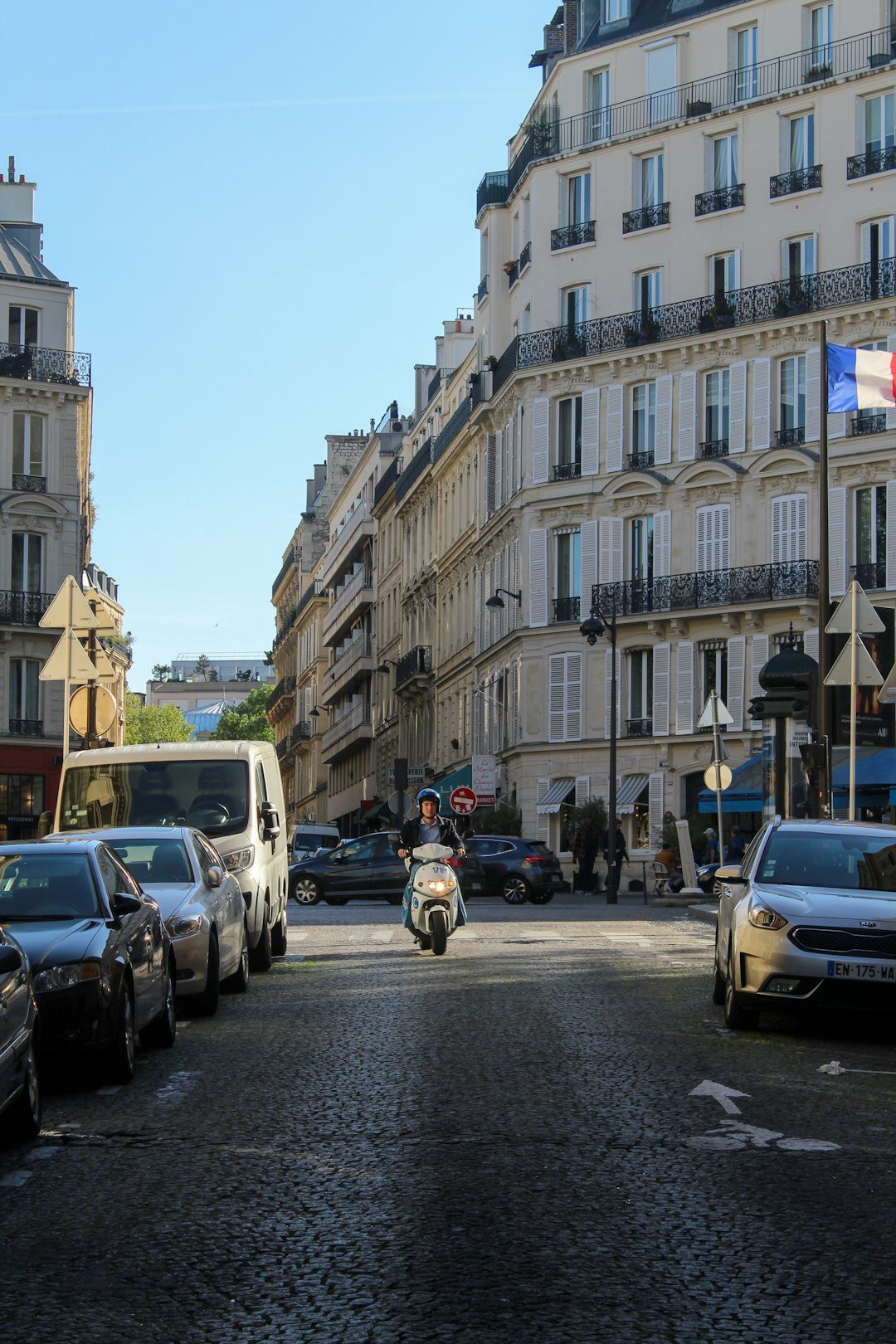 A scooter rides down a parisian street.