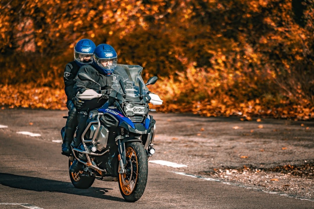Two people riding a motorcycle in autumn