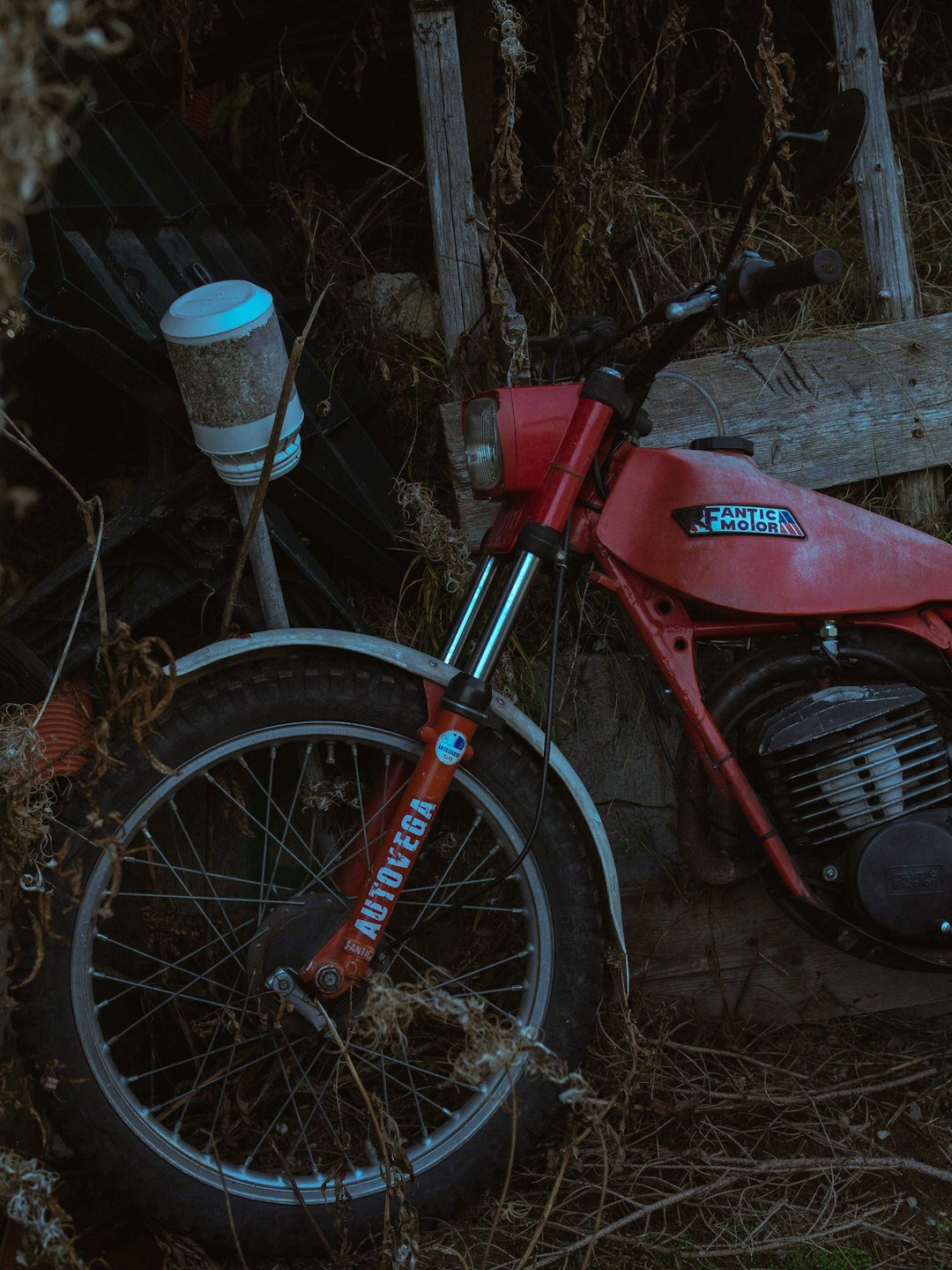 A red motorcycle parked next to a wooden fence