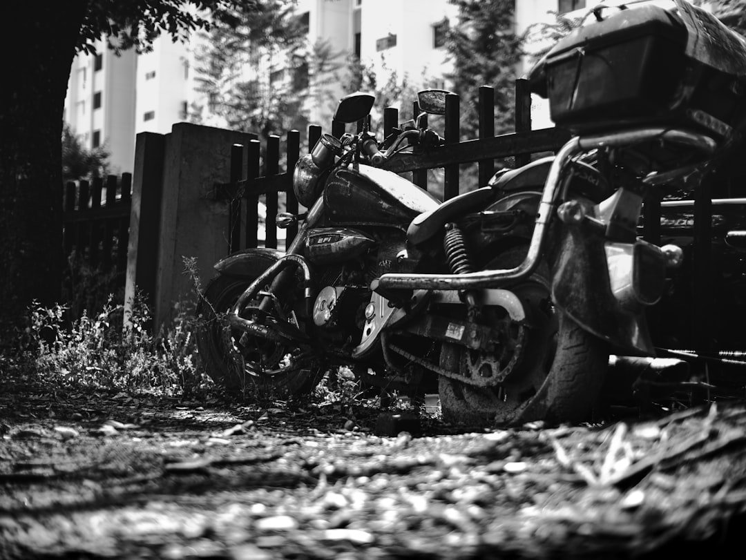 A black and white motorcycle parked outdoors near a fence.