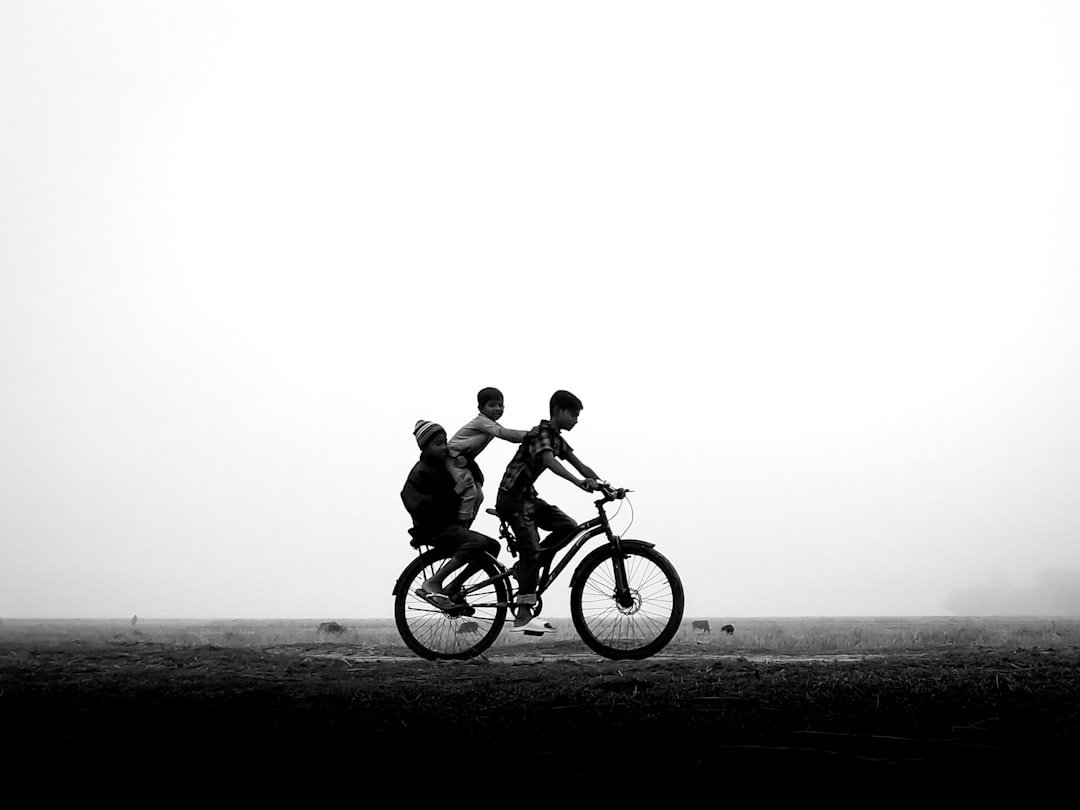 Three children ride a bicycle together outdoors