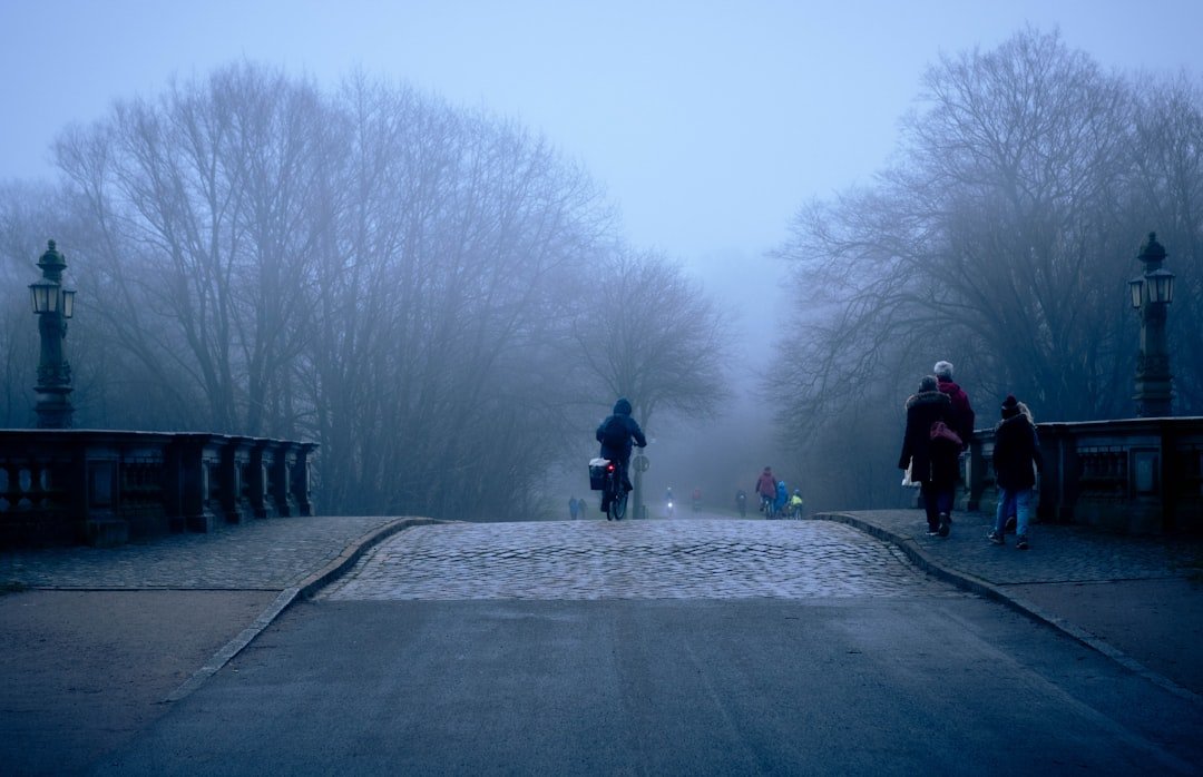 A group of people walking across a bridge on a foggy day