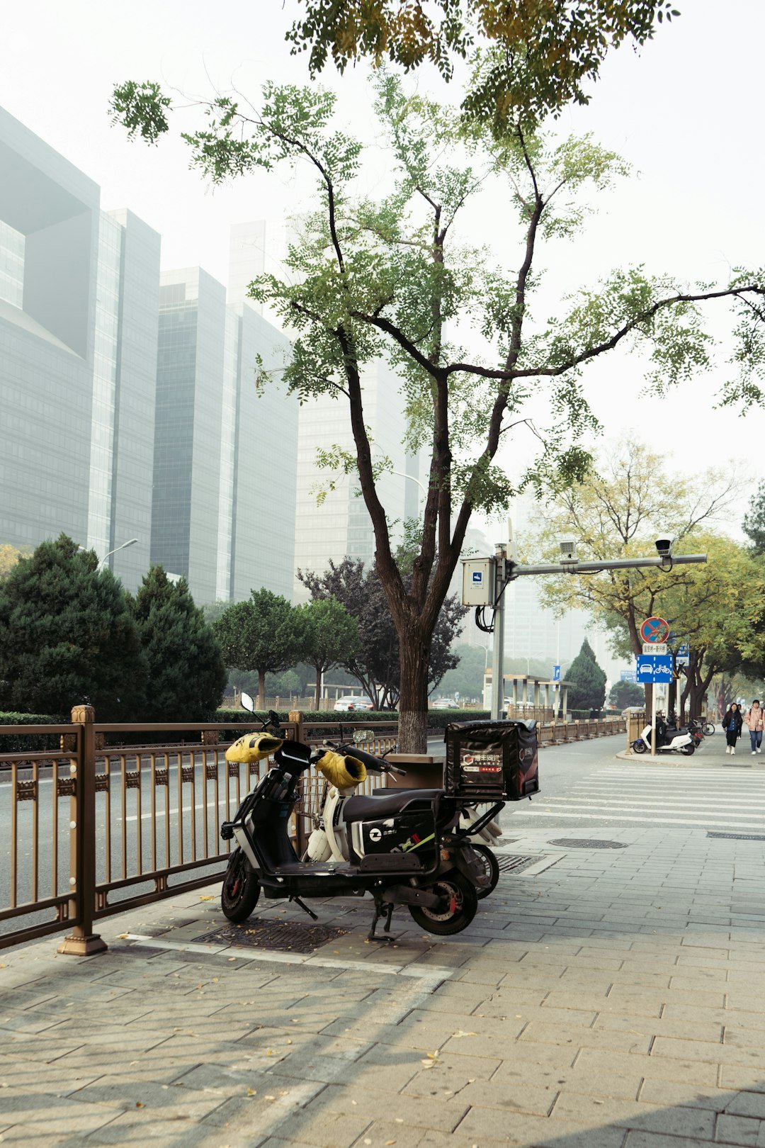 A scooter parked on the side of a road next to a tree