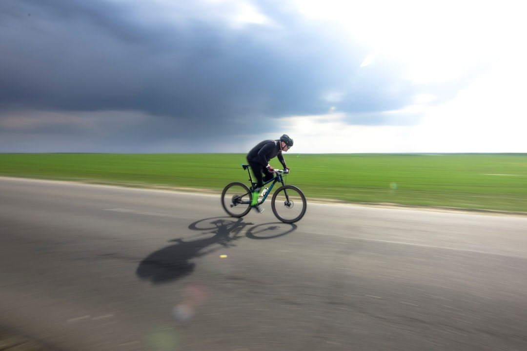 a man riding a bike down a road under a cloudy sky